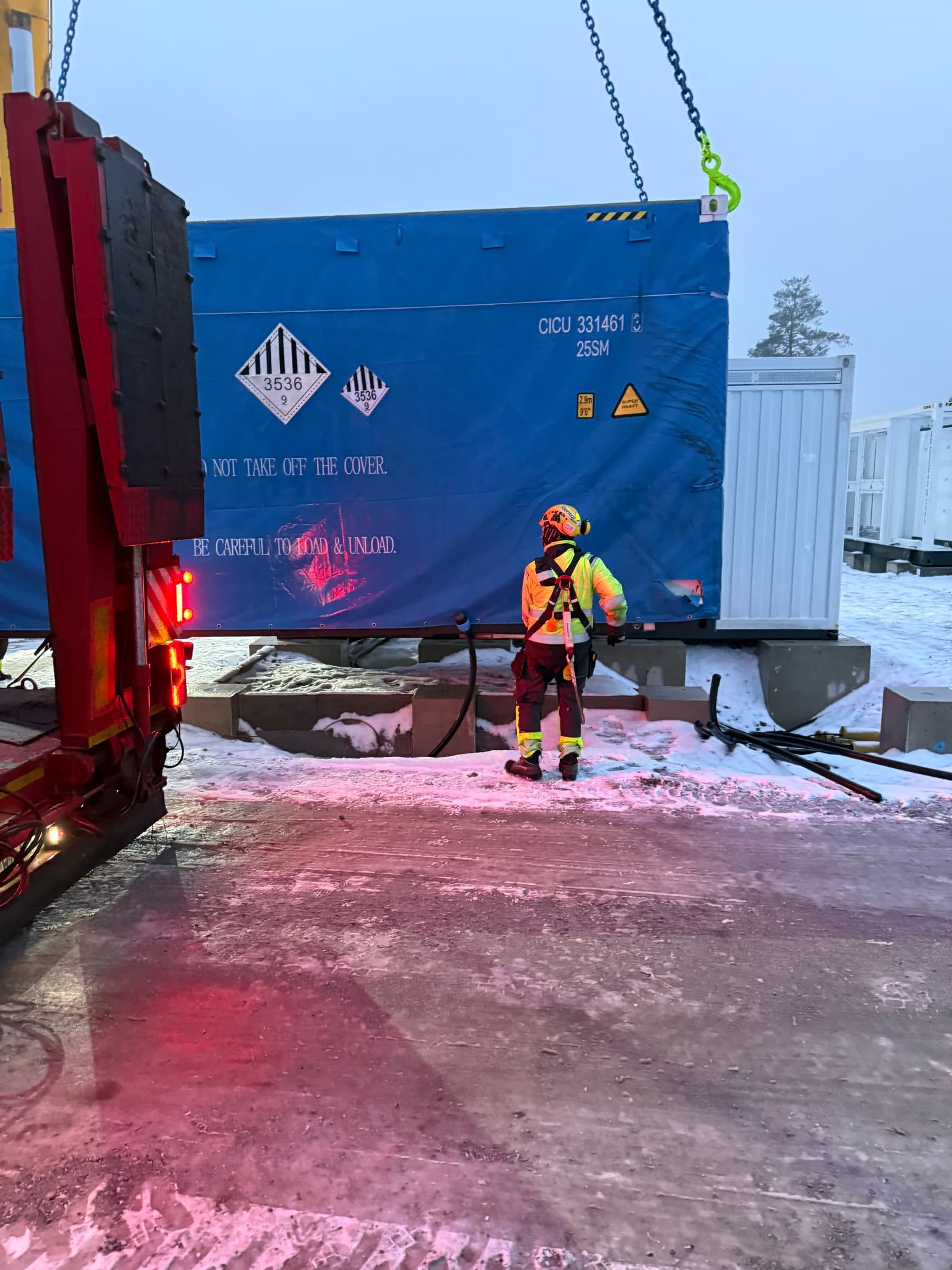 Contenedor de batería descargado de un remolque en la nieve bajo luz nocturna