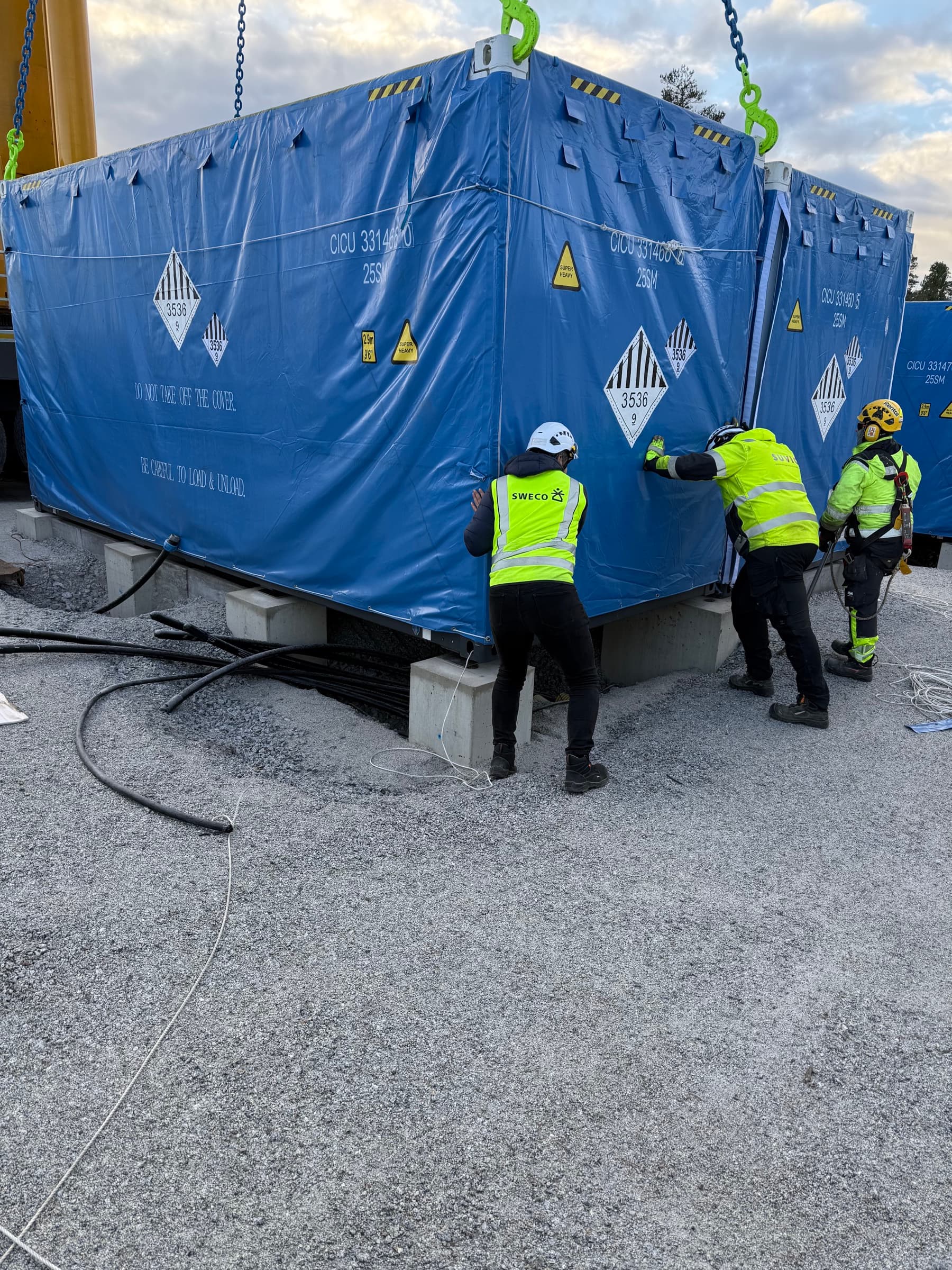 Trabajadores guiando el contenedor de batería a su posición